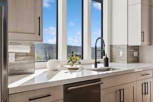 Kitchen with dishwasher, backsplash, a sink, light countertops, and a mountain view