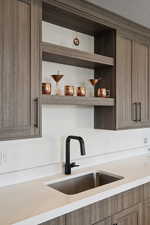Kitchen with a sink, open shelves, and light countertops