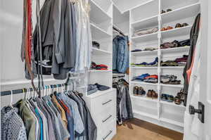 Walk in closet with light hardwood / wood-style floors