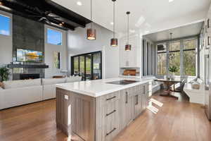 Kitchen with light wood finished floors, a large fireplace, light countertops, white cabinetry, and high vaulted ceiling