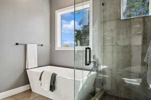 Bathroom featuring a shower stall, a freestanding bath, and baseboards