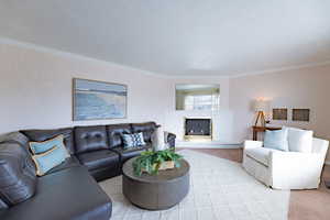 Carpeted living room with a fireplace, a textured ceiling, and crown molding