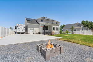 View from back yard looking towards house including a fire pit, a patio, and solar panels