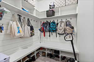 Mudroom just inside of garage entrance featuring shelving and storage hooks