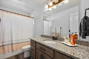 Bathroom featuring hardwood / wood-style floors, oversized vanity, toilet, and a textured ceiling