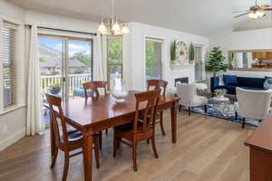 Dining room with light wood flooring, vaulted ceiling, and ceiling fan with notable chandelier