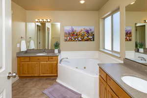 Master Bathroom featuring tile floors, dual sinks, oversized vanity, and a jetted tub