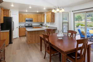 Kitchen with light hardwood / wood-style flooring, kitchen peninsula, a notable chandelier, sink, and appliances with stainless steel finishes