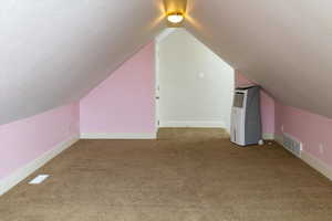 Bonus room featuring dark colored carpet and lofted ceiling