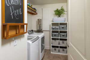 Laundry room featuring light tile floors and washing machine and clothes dryer