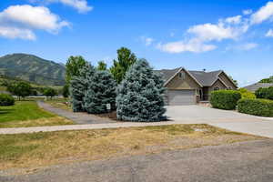 View of front facade featuring a garage and a mountain view with horseshoe game & walking / biking trail