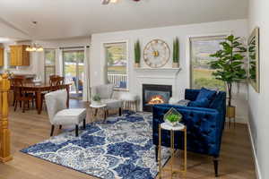 Living room with ceiling fan with notable chandelier and hardwood floors & fireplace