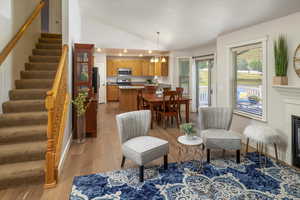 Sitting room featuring a notable chandelier, light hardwood floors, vaulted ceiling, and fireplace