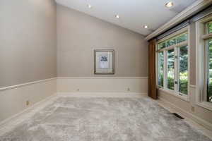 Formal living off foyer with carpet floors and a lofted, grand ceiling