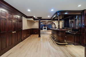 Wet Bar featuring cherry cabinetry, ornamental molding, light hardwood / wood-style floors, and ornate columns.