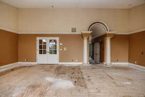 Primary suite with french doors to hallway, and ornate columns, (Price adjusted so buyers can customize flooring to their preference after closing.)