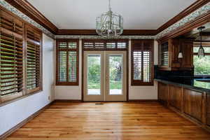 Interior space featuring an inviting chandelier, wood molding, and hardwood flooring. Patio doors to exterior. Wood blind shutters throughout.