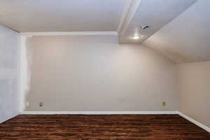 Bedroom with LVP  flooring, a textured ceiling, and vaulted ceiling.  (Use to be adjoined to other blue bedroom.  That's the added wall to the left in the photo. Just needs the finish paint.)