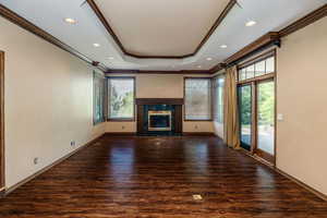 Family/ media room with a gas fireplace, a tray ceiling, crown molding, and hardwood flooring.  Beautiful built-in cabinets & Shelving flank each side of the french doors.  Second entrance into the kitchen and patio door to the covered patio.