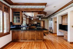 Kitchen featuring hanging light fixtures, ornamental molding, and kitchen peninsula