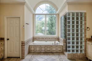 Bathroom with a jetted tub, tile flooring, and extensive, dual vanities.  Splendid block glass in step-in shower.