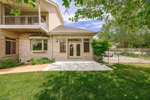 Exterior space featuring a yard, a patio area, a balcony above, and french doors to kitchen dining area.