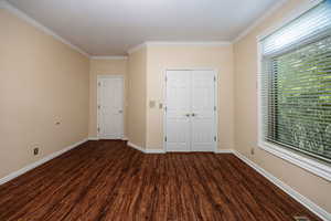 Main floor bedroom with  LPV/ wood flooring, ornamental molding, and a closet