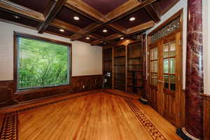 Office with built-in shelving, featuring coffered ceiling, light hardwood / wood-style floors, and wood trimmed ceiling