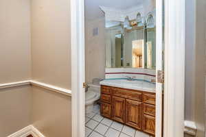 Guest Bathroom featuring tile floors, crown molding, vanity, and toilet