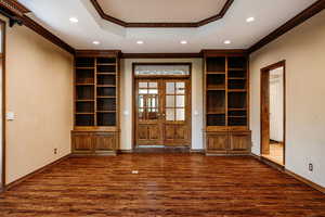 Living/media room with crown molding, french doors, and gorgeous hardwood floors.  Door to covered patio, kitchen and foyer.