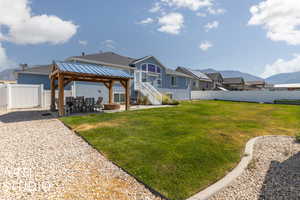 Rear view of property with a mountain view, a lawn, a gazebo, and a patio