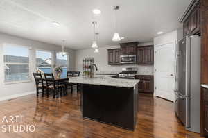 Kitchen featuring  stainless steel appliances, a kitchen island with sink, pendant lighting, and sink