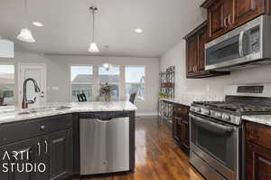 Kitchen with appliances with stainless steel finishes, sink, and pendant lighting