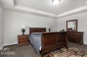 Carpeted bedroom with a tray ceiling