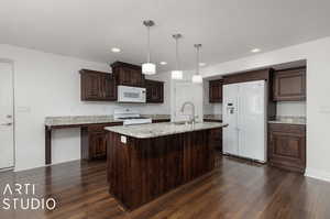 Kitchen with white appliances, an island with sink, pendant lighting,