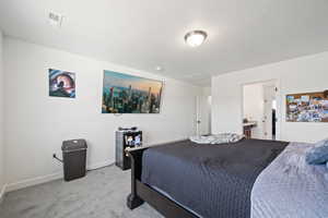 Bedroom featuring ensuite bathroom and light colored carpet