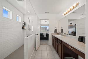 Bathroom featuring a tile shower, vanity, and tile floors