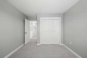 Unfurnished bedroom featuring light carpet and a closet