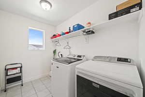 Laundry room with washing machine and clothes dryer and light tile floors