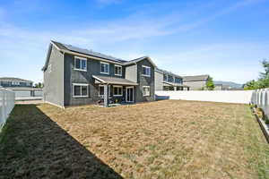 Rear view of house featuring a lawn and solar panels