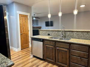 Kitchen featuring light wood-type flooring, decorative light fixtures, sink, ceiling fan, and stainless steel dishwasher