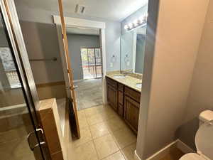 Bathroom with a textured ceiling, vanity, toilet, and tile patterned floors