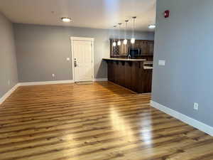 Kitchen featuring decorative light fixtures, hardwood / wood-style floors, kitchen peninsula, decorative backsplash, and a breakfast bar