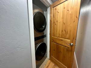 Laundry area with light wood-type flooring and stacked washer and dryer