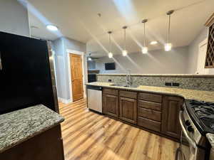 Kitchen with pendant lighting, light hardwood / wood-style flooring, stainless steel appliances, sink, and ceiling fan