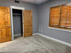 Unfurnished bedroom with a closet and light carpet