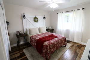 Bedroom with ceiling fan and dark wood-type flooring