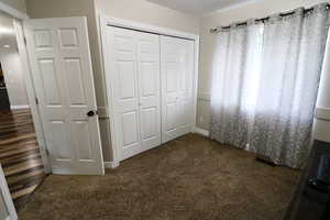 Unfurnished bedroom with a closet and dark carpet