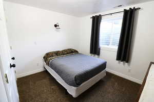 Bedroom featuring a textured ceiling and dark colored carpet