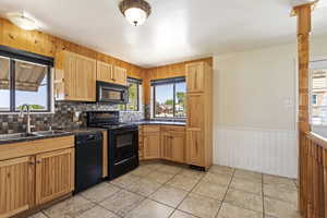 Kitchen with black appliances, sink, tasteful backsplash, and light tile flooring